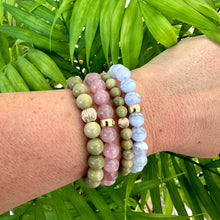 Load image into Gallery viewer, Green Olivine Jasper Bracelet stacked with other bracelets on wrist – natural foliage shot