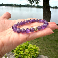 Charger l'image dans la galerie, Amethyst bracelet close up held in hand outdoors by water and trees