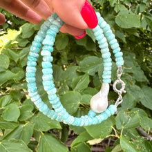 Load image into Gallery viewer, Amazonite and white baroque pearl necklace held in hand against green foliage, natural light view