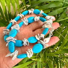 Load image into Gallery viewer, Chunky turquoise and silver grey keshi pearl necklace held in hand against green foliage backdrop