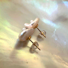 Charger l'image dans la galerie, White flower pearl stud earrings shown on shell from side angle, capturing floral silhouette and radiant iridescence.