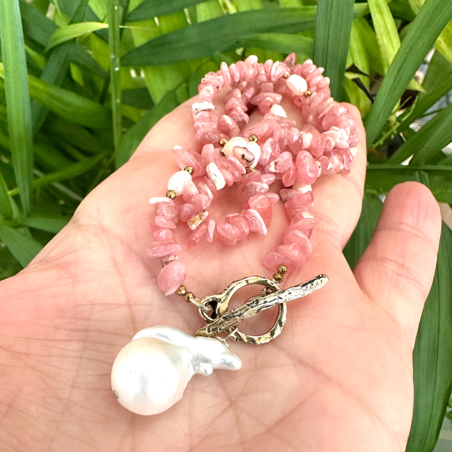 Rhodochrosite pearl toggle necklace held in hand showing pink rhodochrosite nuggets and baroque pearl