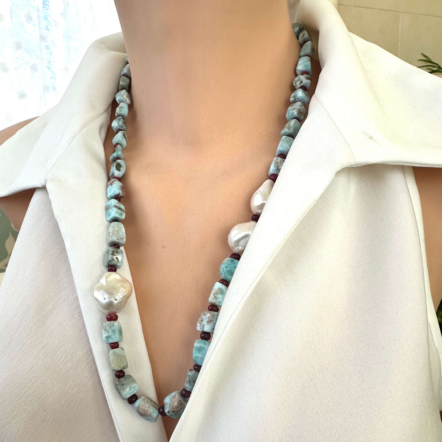 Side angle of larimar ruby and baroque pearl necklace highlighting color contrast