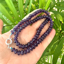 Charger l'image dans la galerie, Close-up of handmade amethyst beaded necklace in dark purple tones against green leaf background