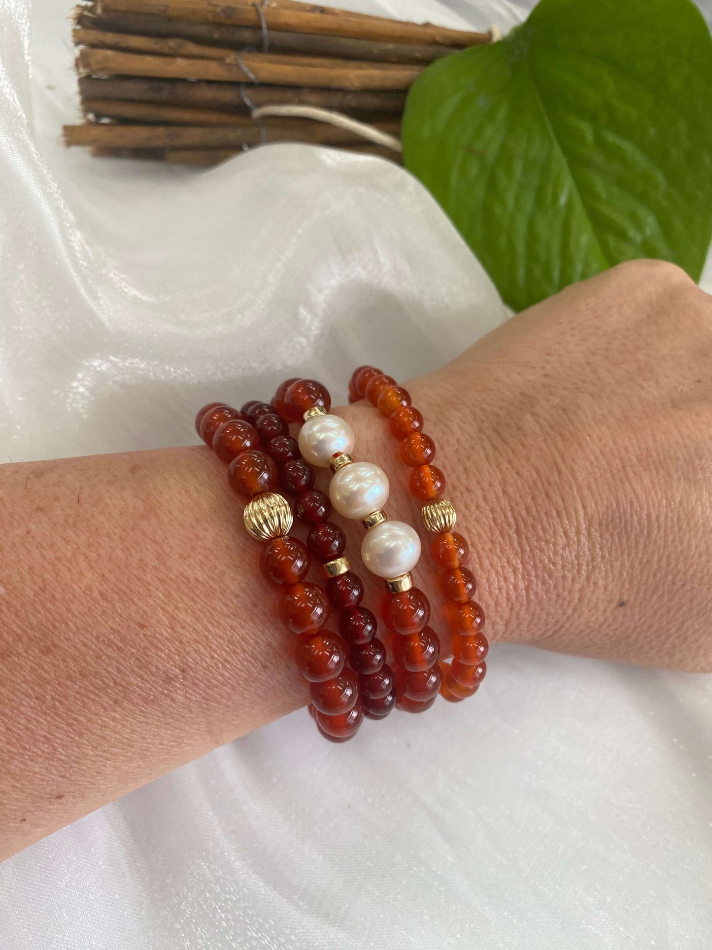 Red agate bracelet featuring 6mm beads and 14K gold filled accents, worn on a wrist with pearl details.
