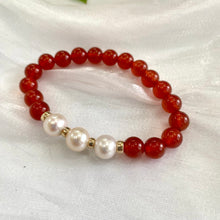 Load image into Gallery viewer, Orange Carnelian Bracelet with three pearls displayed on white cloth – detailed close-up
