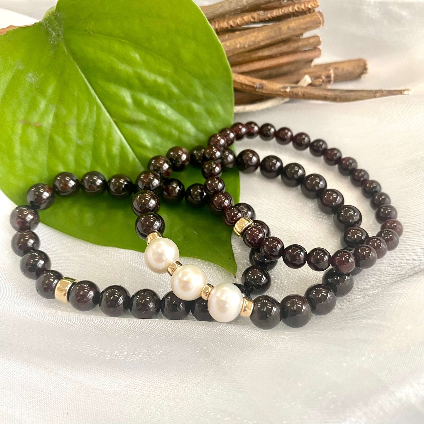 Dark Red Garnet Bracelet trio displayed on white cloth – three-bracelet close-up