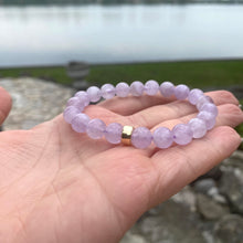 Load image into Gallery viewer, Lavender Amethyst Bracelet shown in hand with lake backdrop – natural light