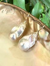 Charger l'image dans la galerie, White baroque pearl drop earrings resting on green leaf and pearl shell backdrop, silver hooks visible