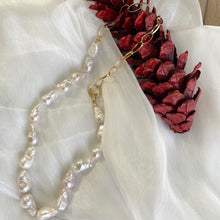 Charger l'image dans la galerie, White baroque pearl and gold chain necklace resting on white cloth with red pine cone, elegant handcrafted jewelry from Canada.