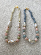 Charger l'image dans la galerie, Morganite and jade necklace with baroque pearls beside blue gemstone necklace on white mat, showcasing color contrast and design variety.