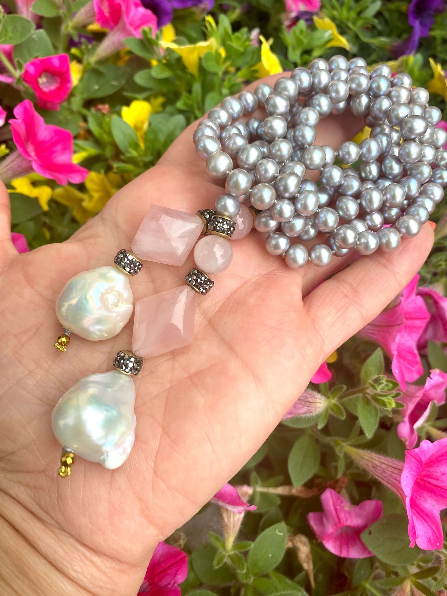 Pastel pearl lariat necklace featuring blue-gray freshwater pearls and pink rose quartz, set against colorful flowers.