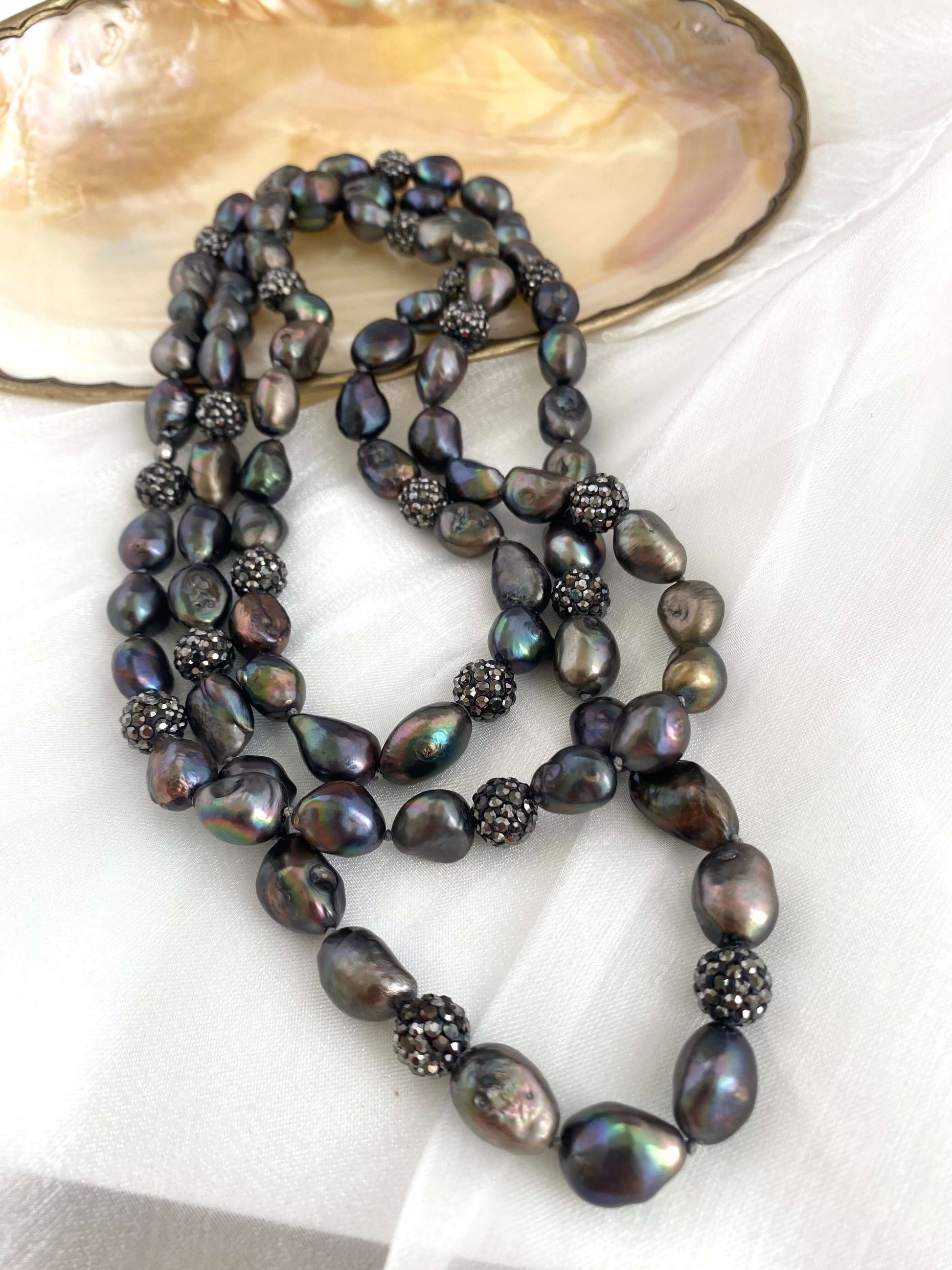 Very long peacock pearl necklace featuring iridescent freshwater pearls and rhinestone spacer beads.