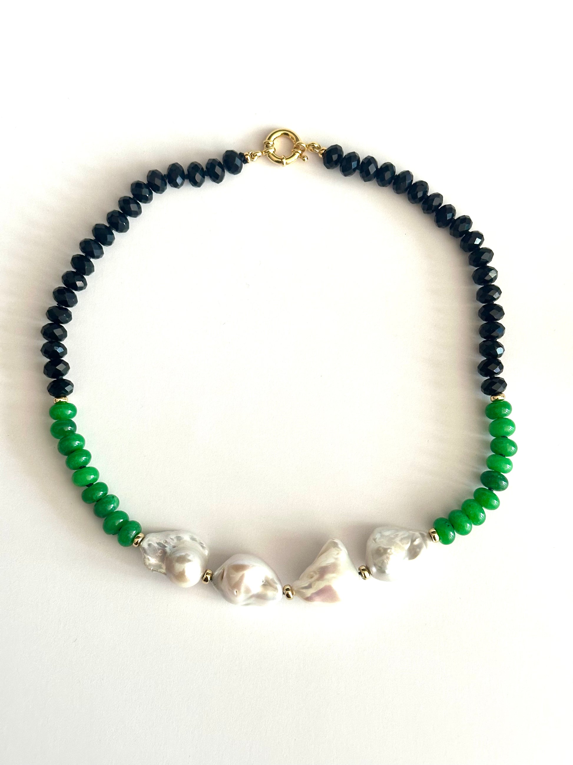 A beaded necklace featuring BLACK TOURMALINE faceted beads on one side, bright green JADE beads on the other, and 4 irregular white baroque pearls in the center, finished with a gold clasp.