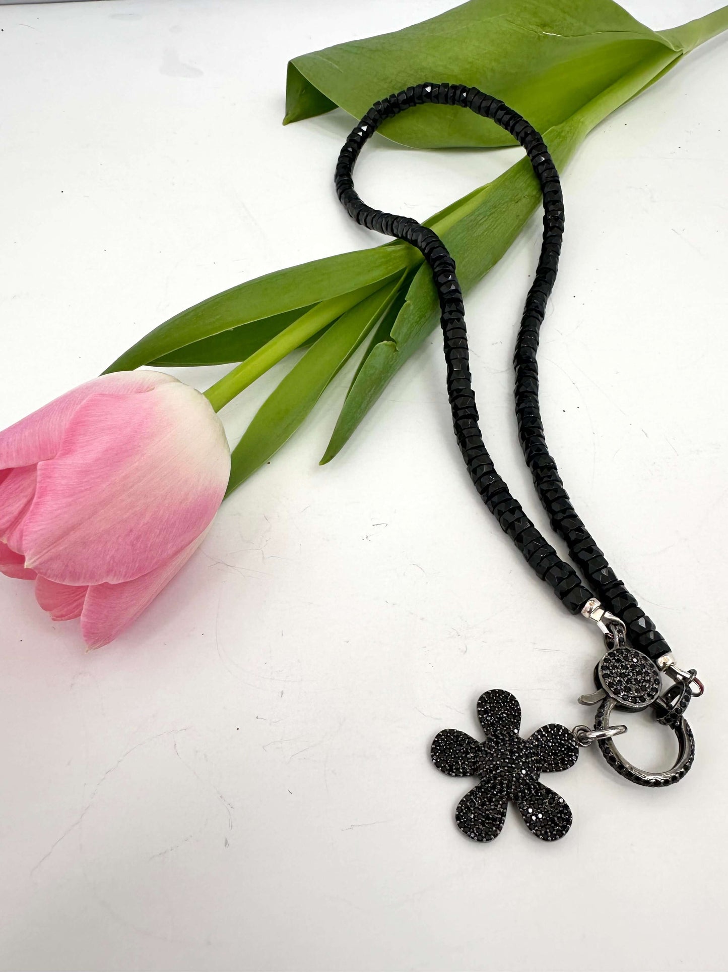 Black spinel daisy pendant necklace in oxidized silver with black heishi beads and flower charm.
