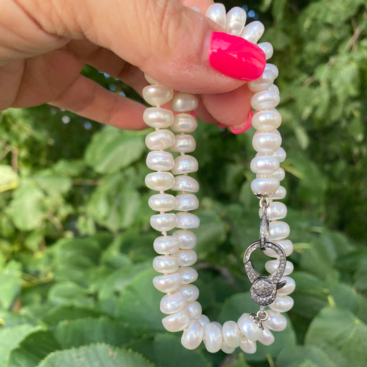 Button pearl necklace with diamond pavé held in hand showing hand-knotted freshwater button pearls