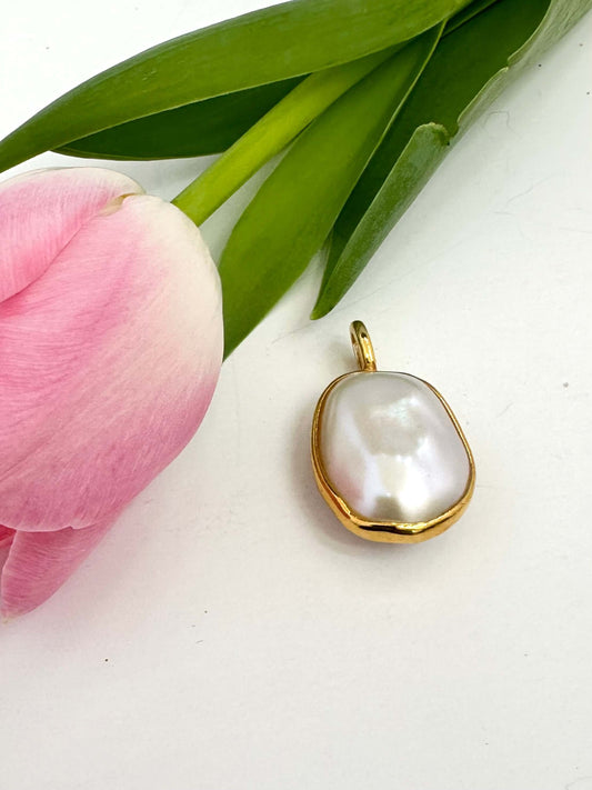 Baroque pearl pendant in gold vermeil beside a pink tulip, showcasing a luminous freshwater pearl charm.