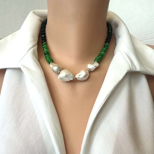 A close-up of a necklace worn on a mannequin or model torso, featuring 4 large irregular white baroque pearls in the center, flanked by green beads and black beads, styled with a white collared shirt.