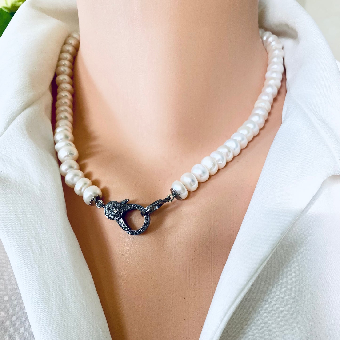Button pearl necklace with diamond pavé worn on model sitting elegantly at the collarbone