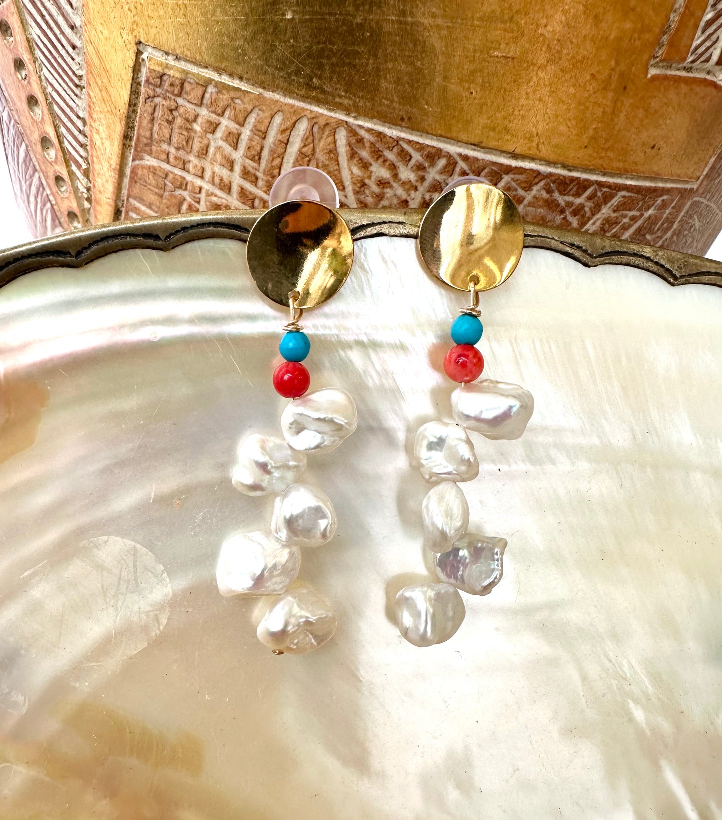 Close-up of Baroque Keshi Pearl Earrings on pearl shell with gold vase background, showing elegant handmade craftsmanship