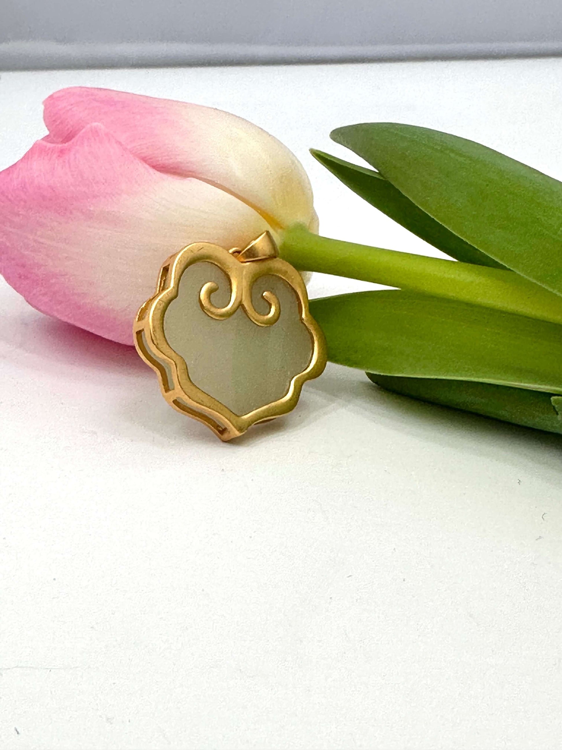 Hotan jade pendant in gold vermeil showcasing natural nephrite charm next to a pink tulip.