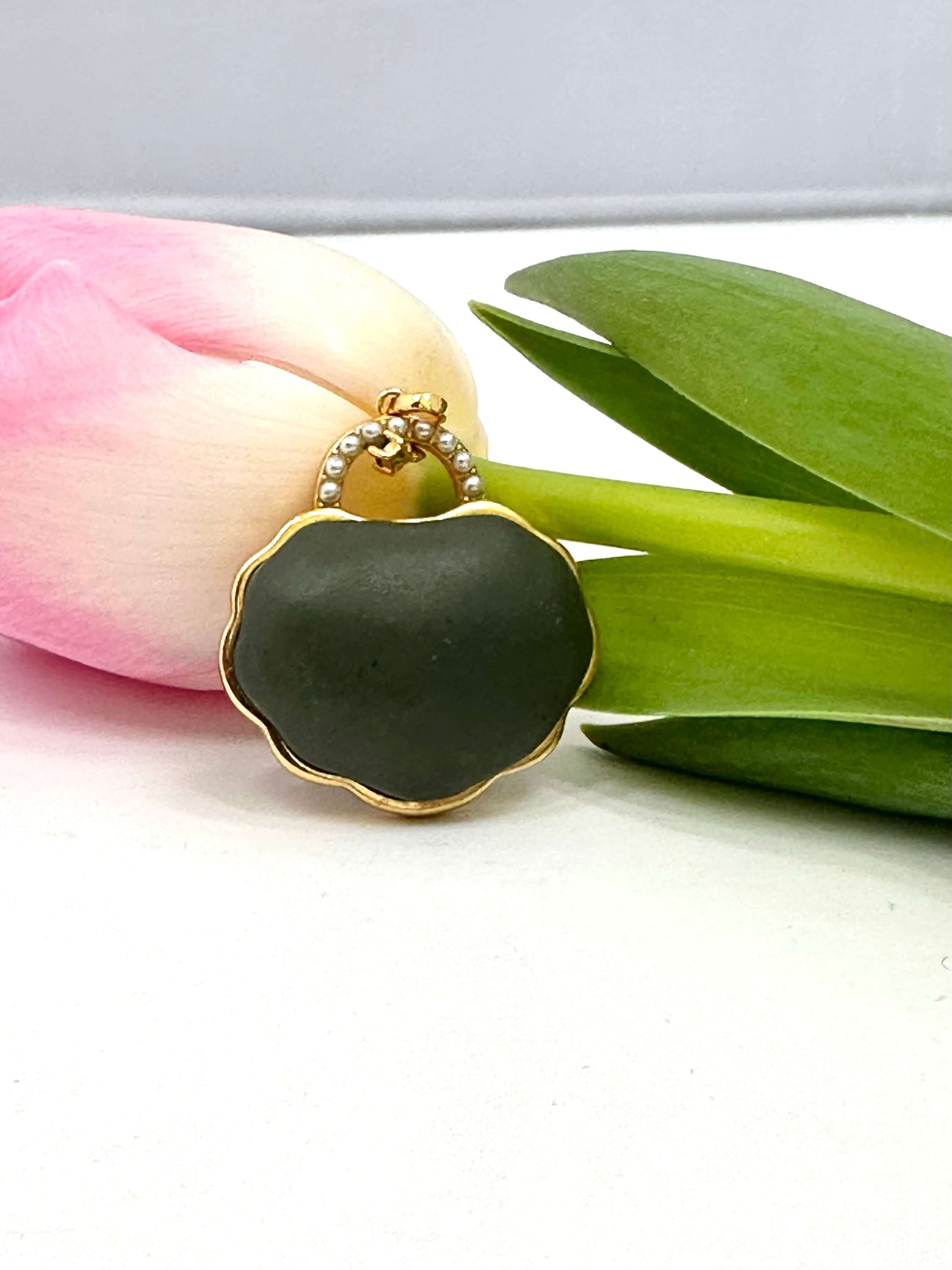 Hotan jade purse pendant with pearl detail in gold vermeil beside a pink tulip.