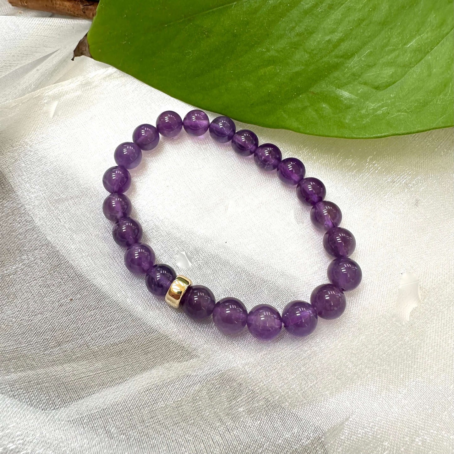 Amethyst Bracelet close-up on white cloth – purple bead detail shot