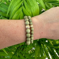 Green Olivine Jasper Bracelet worn on wrist against green leaves – outdoor detail