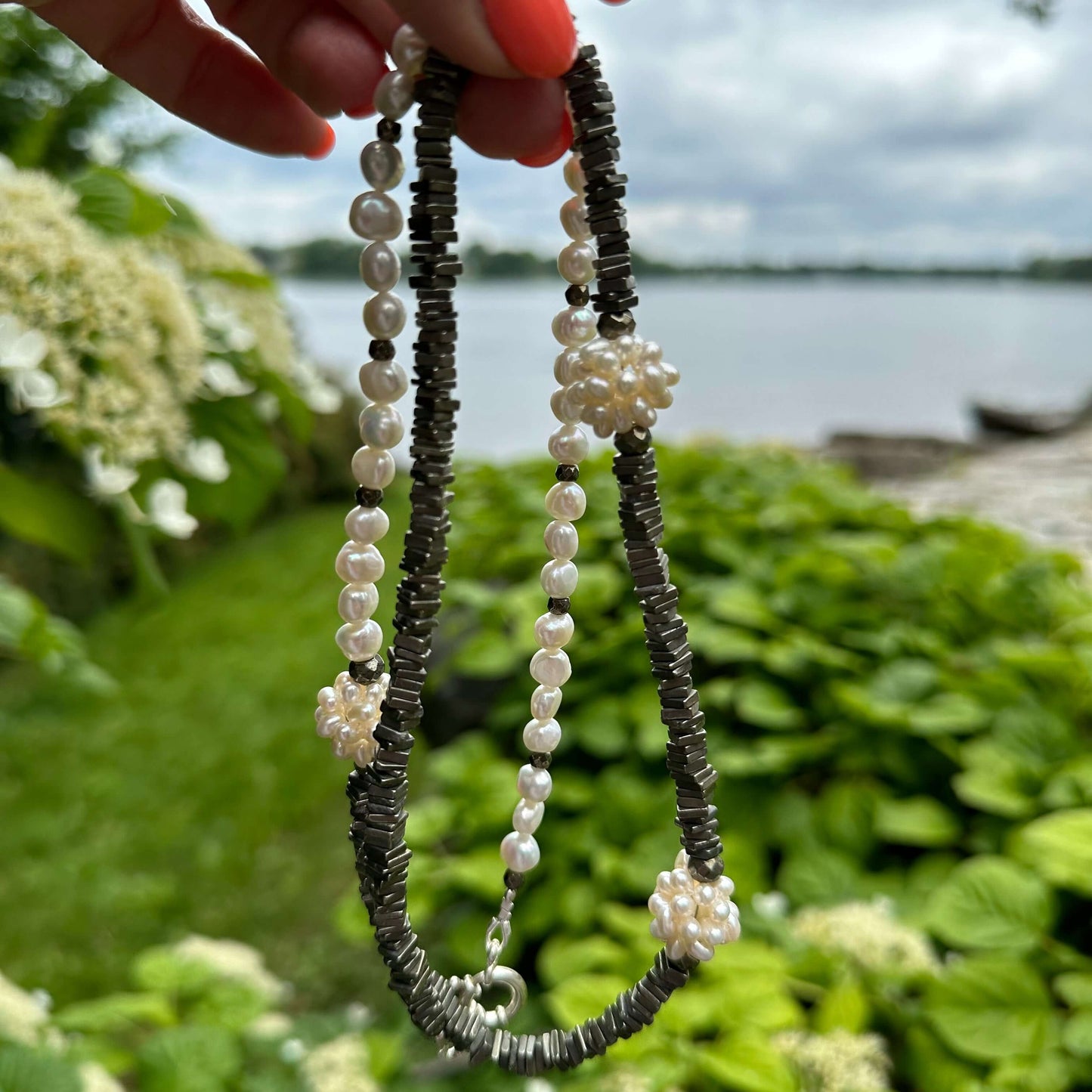 Close up of pyrite and pearl necklace outdoors with greenery
