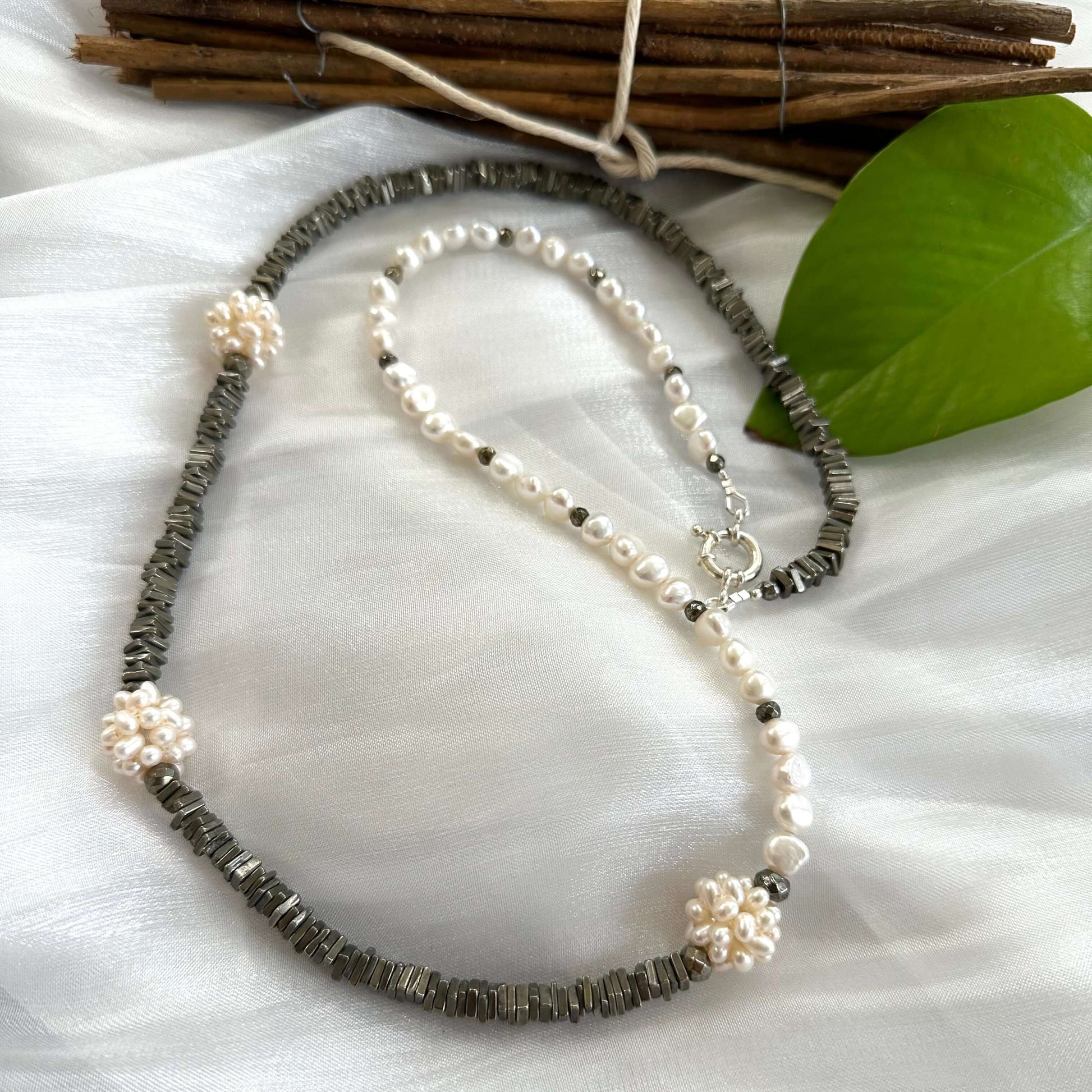 Pyrite and pearl necklace displayed on white cloth background