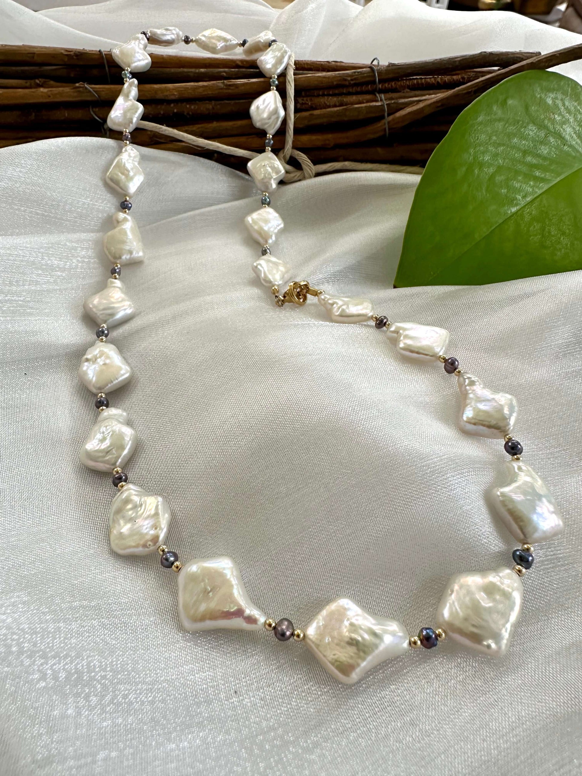 Black and White Pearl Necklace displayed on white cloth – product detail close-up