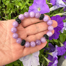 Load image into Gallery viewer, Lavender jade bracelet without pearl held in hand near purple flowers
