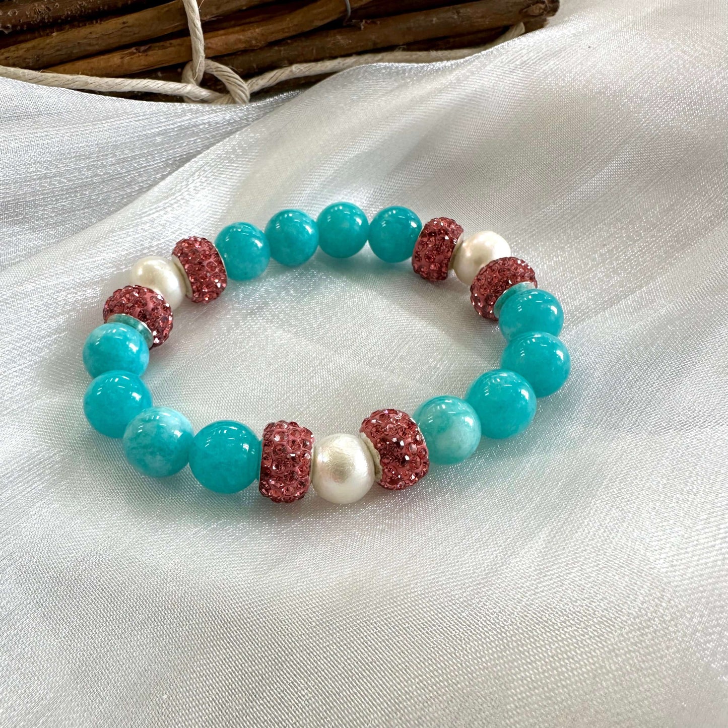 Teal jade bracelet with pearls and pink rhinestones showcasing vibrant colors and handmade craftsmanship.