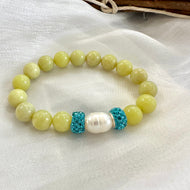 Olive green jade bracelet with one pearl displayed on white cloth