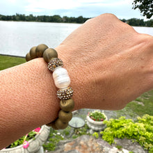 Load image into Gallery viewer, Gold druzy agate bracelet with pearl worn on a woman’s wrist outdoors
