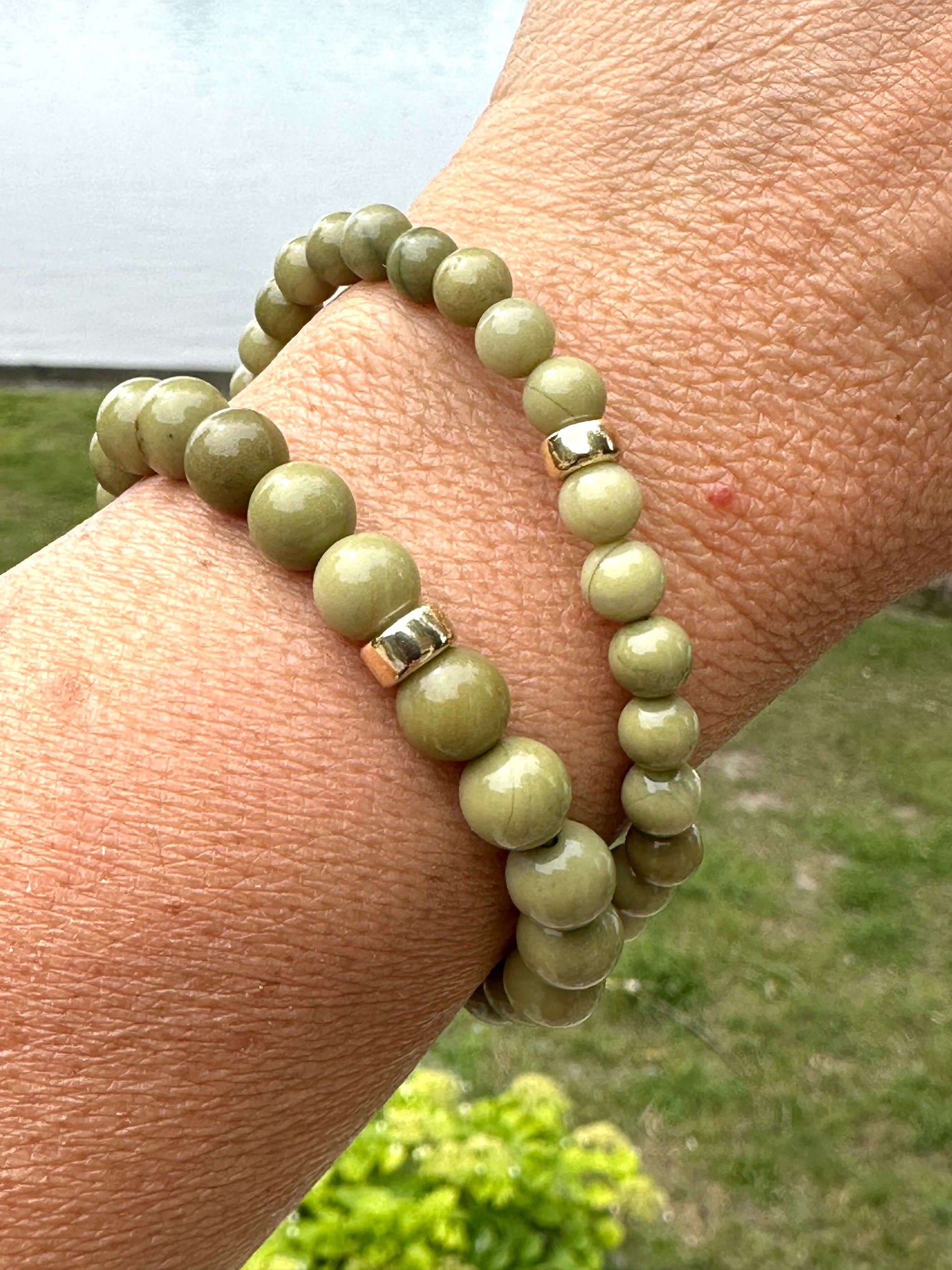 Olive green jasper bracelet on wrist showcasing 6mm and 8mm beads with gold-filled accents.