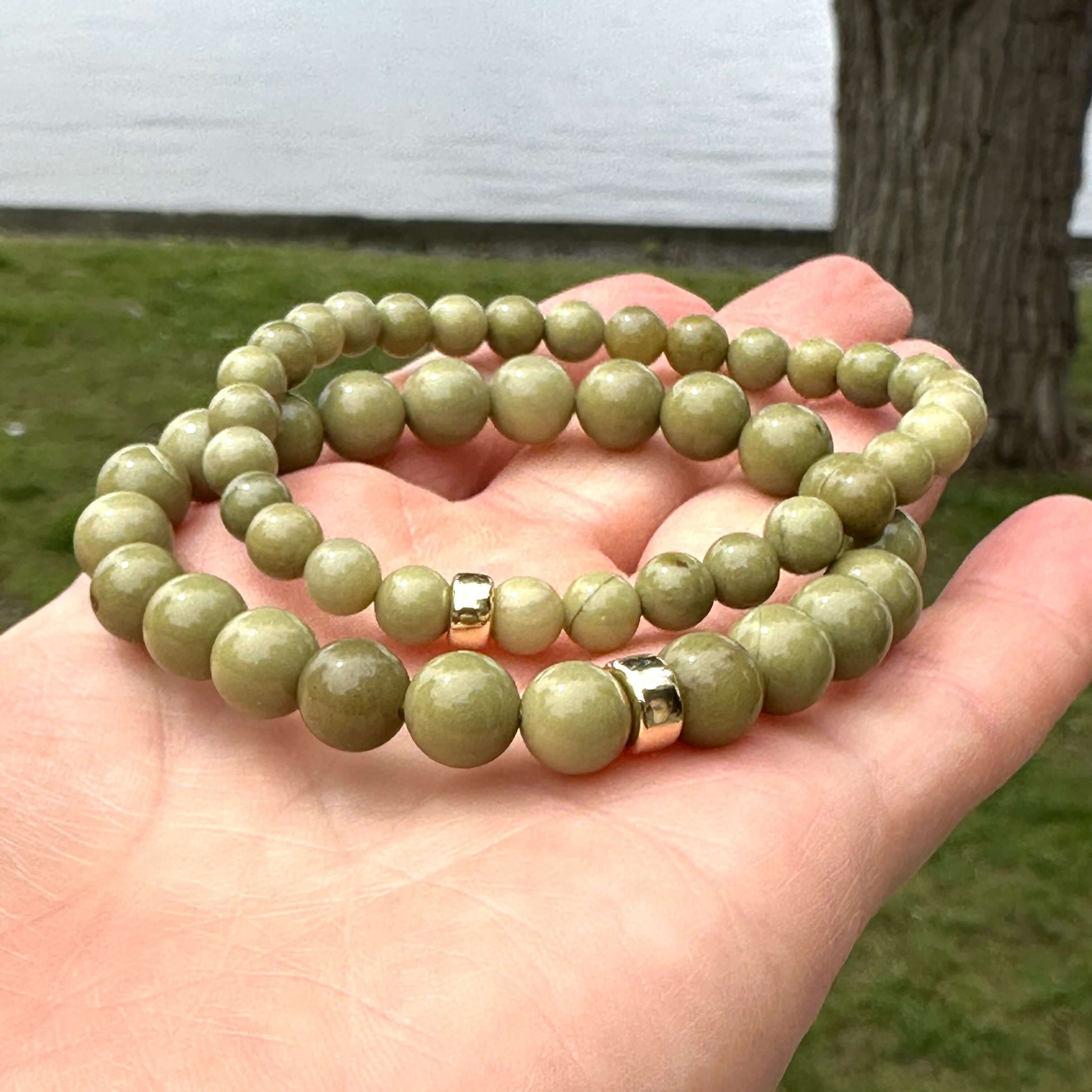 Olive green jasper bracelet – 6mm or 8mm, hand-strung with 14K gold filled accents in a person's hand.