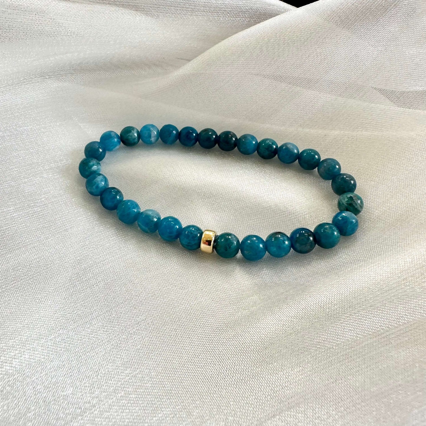 Blue Apatite Bracelet close-up on white surface – gemstone bead detail