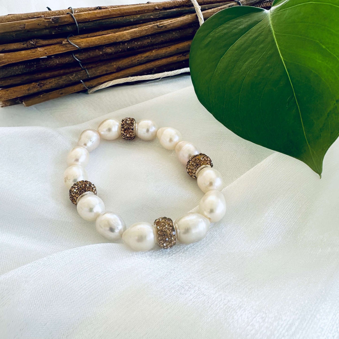 Close-up of white pearl stretch bracelet with champagne rhinestone bead on white cloth