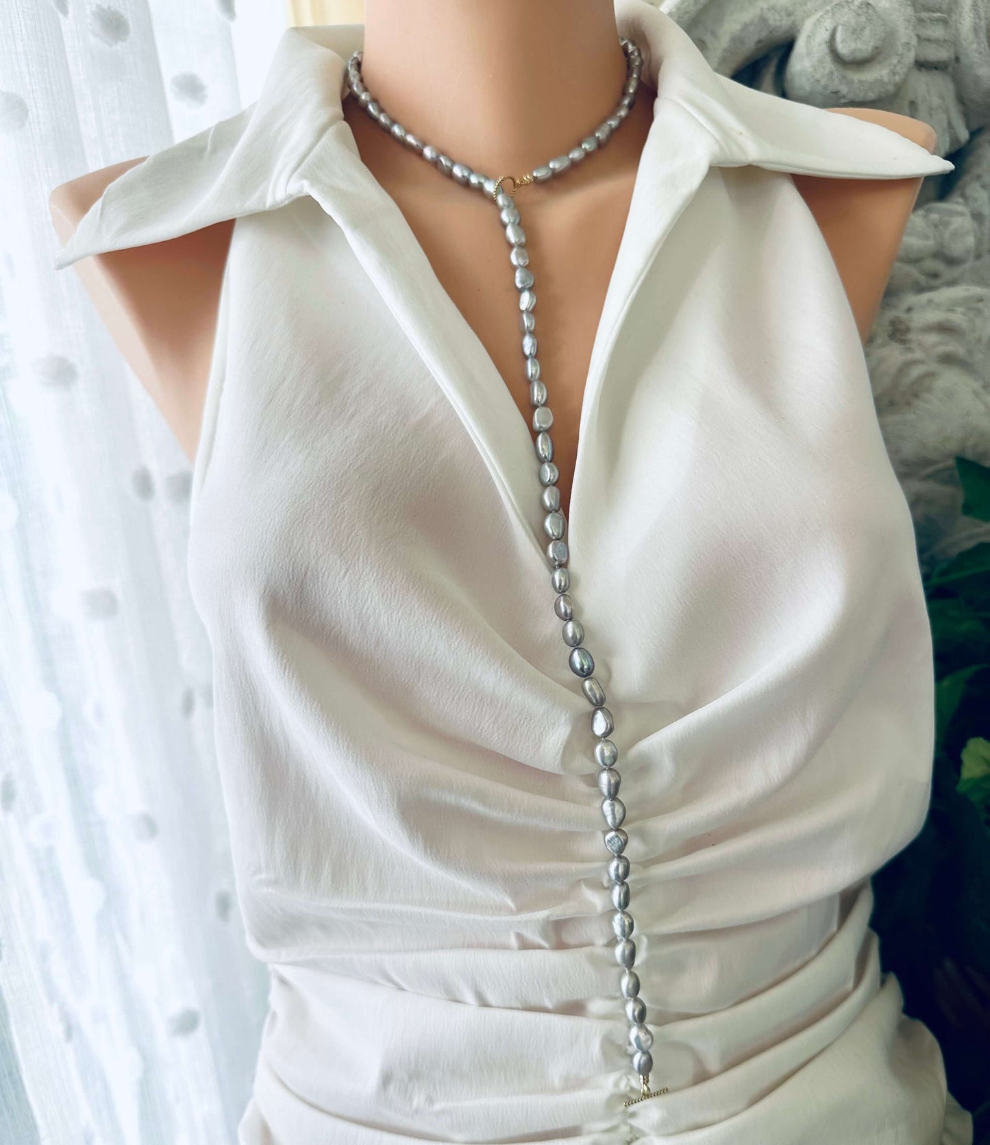 Grey nugget pearl necklace displayed elegantly on a mannequin wearing a white blouse.