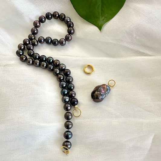 Black pearl necklace with baroque pendant shown next to removable pendant on white cloth