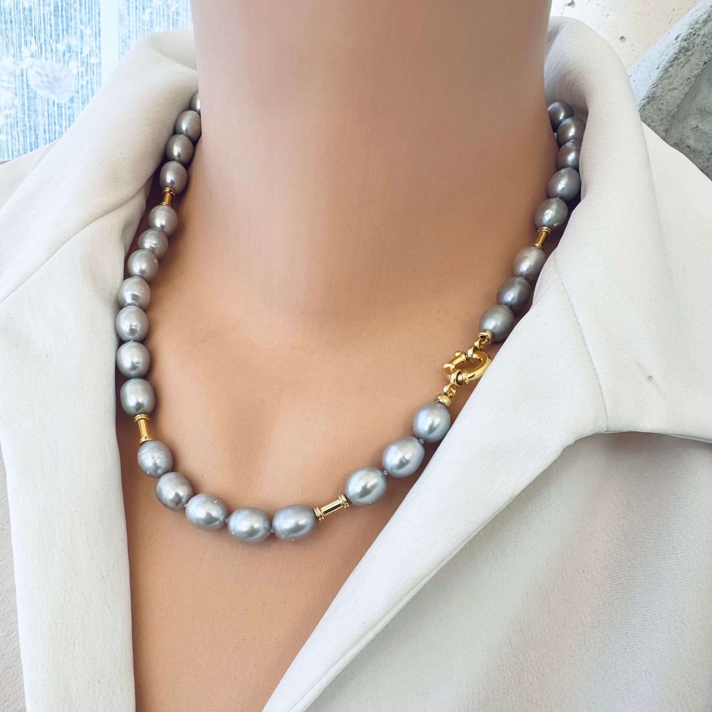 Grey pearl necklace with gold details displayed on mannequin, frontal close-up
