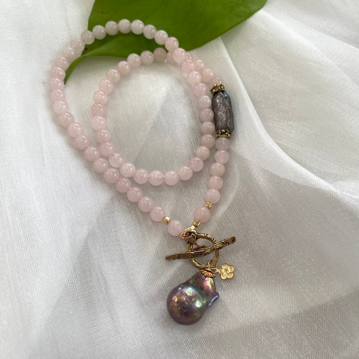 Rose quartz toggle necklace with black baroque pearl, showcasing delicate blush-pink beads and unique pendant.
