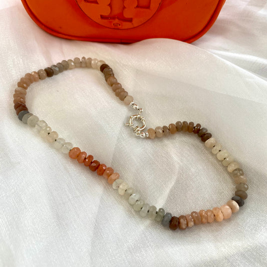 Moonstone candy necklace with sunstone beads, showcasing a mix of iridescent gems on a soft fabric background.
