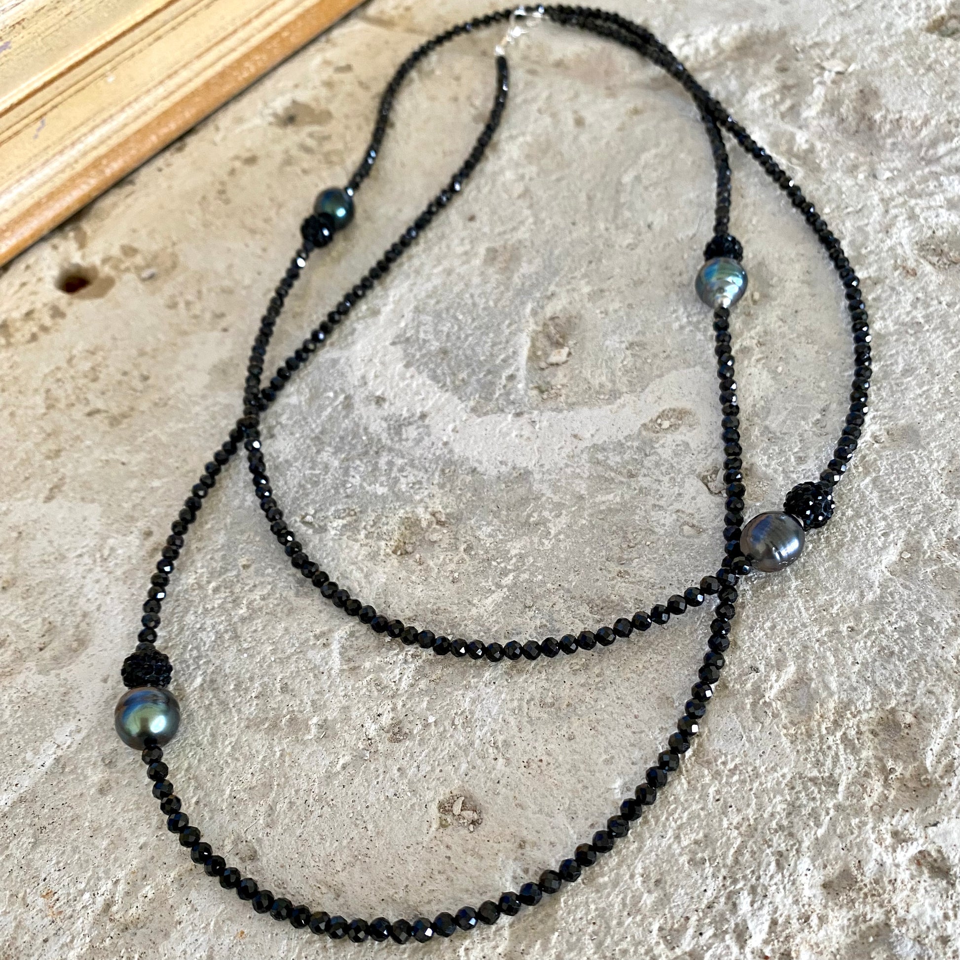 Black spinel pearl necklace displayed against natural stone background