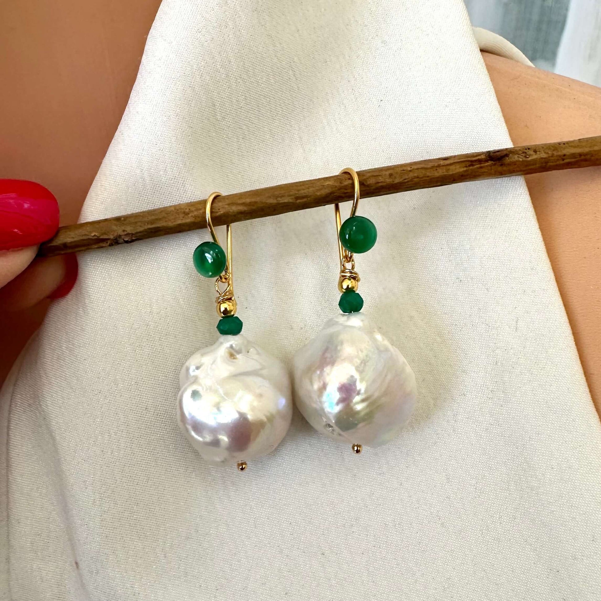 White baroque pearl drop earrings with green agate showcased in elegant display.