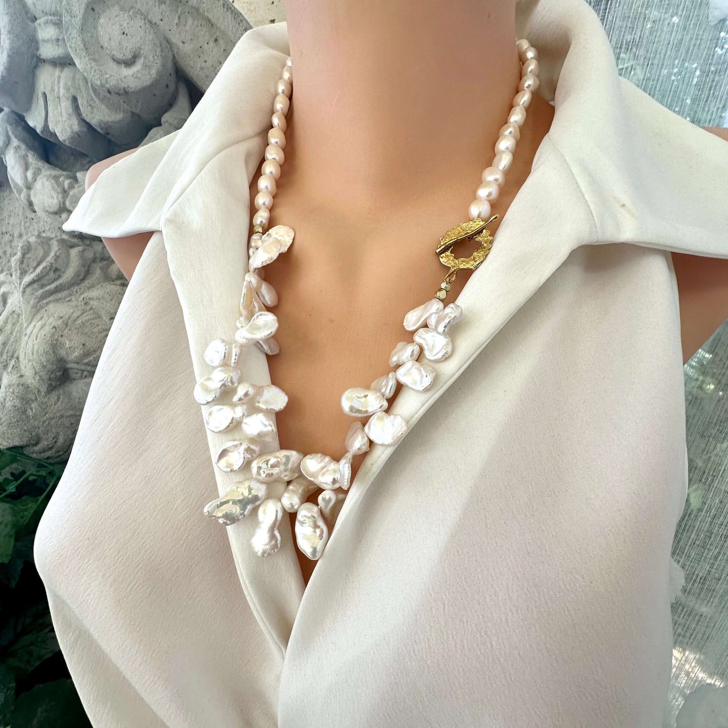 Side view of white keshi pearl necklace displayed on mannequin highlighting asymmetrical design