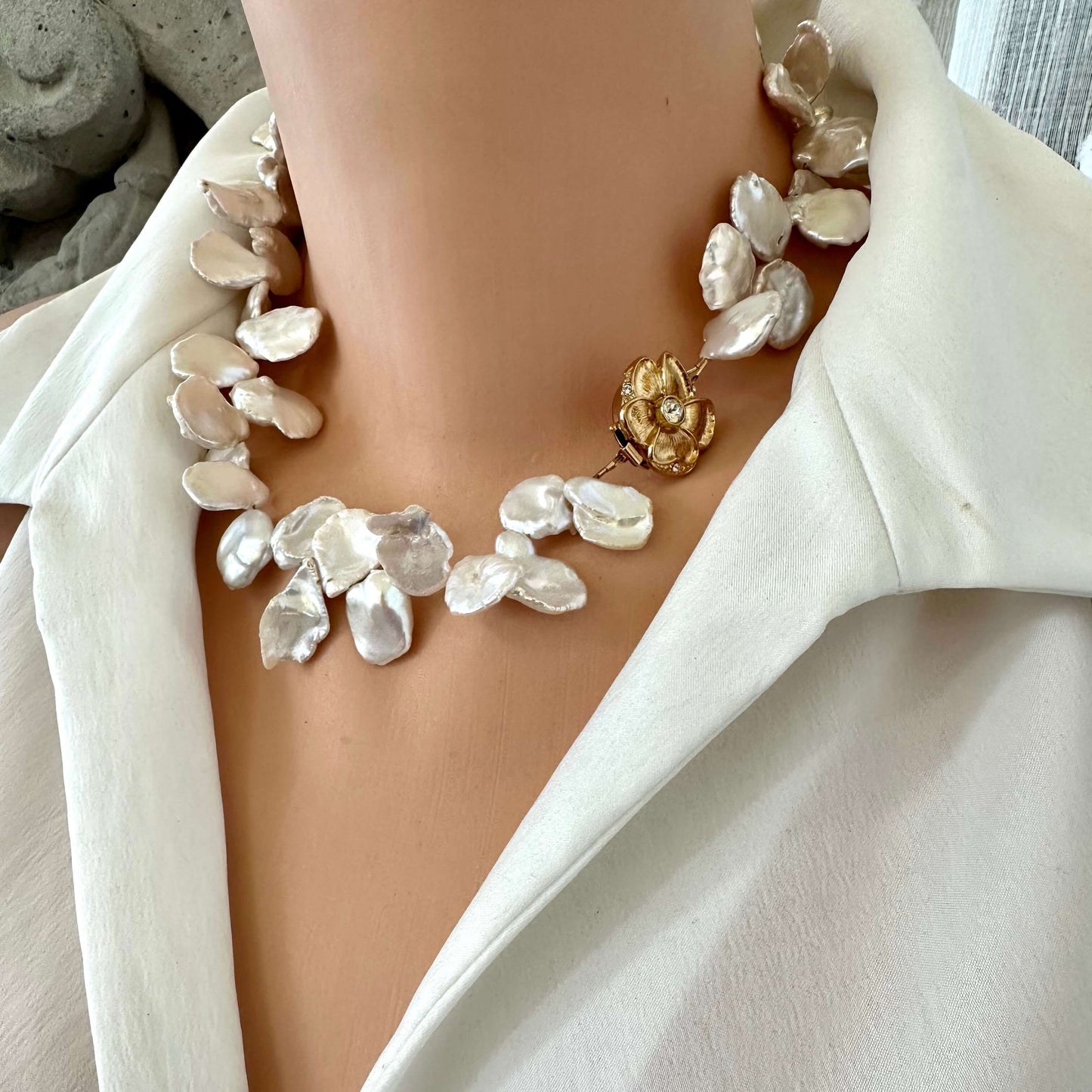 White keshi pearl necklace with flower clasp worn by mannequin, side close-up view