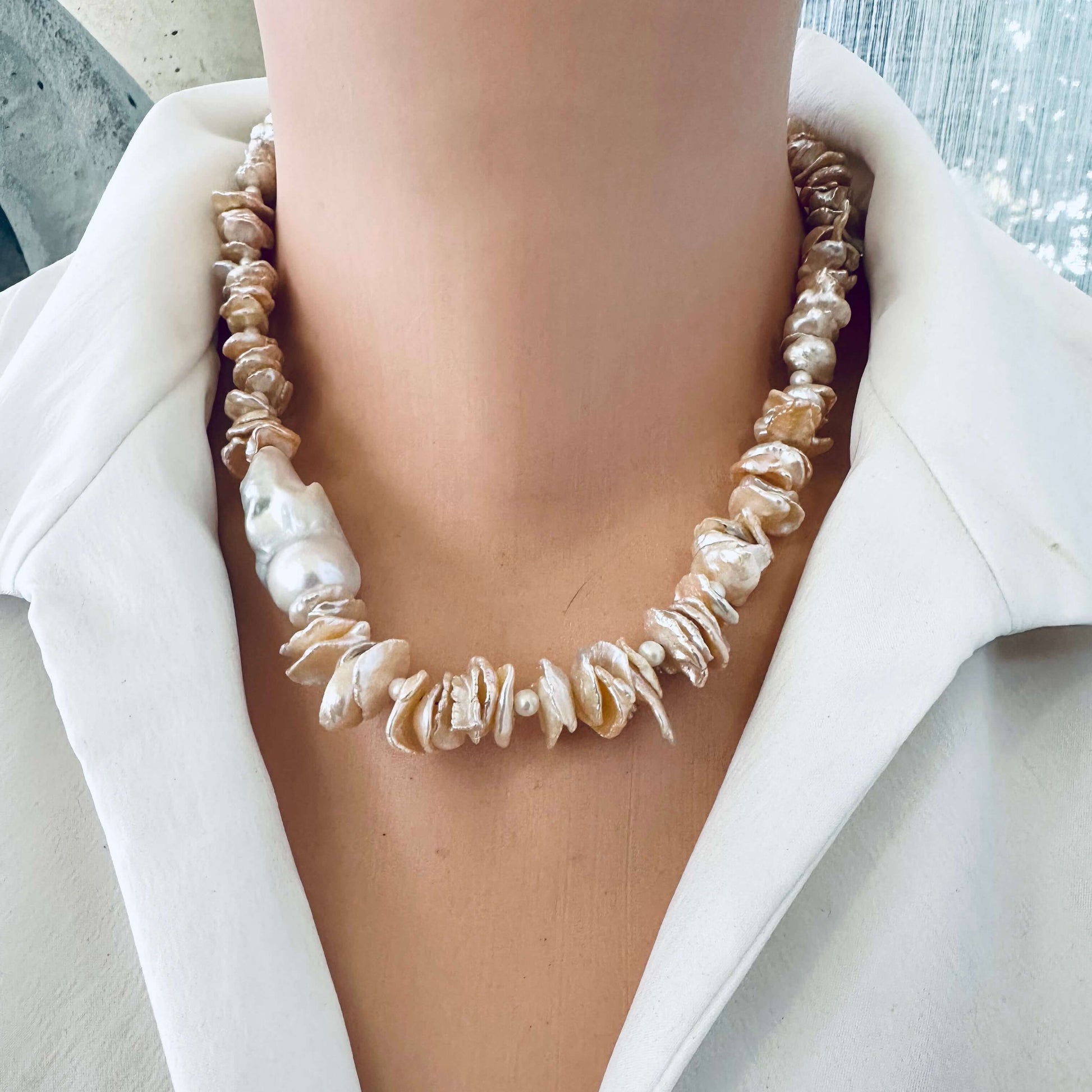 Peach keshi pearl necklace displayed on mannequin wearing white blouse, frontal close-up