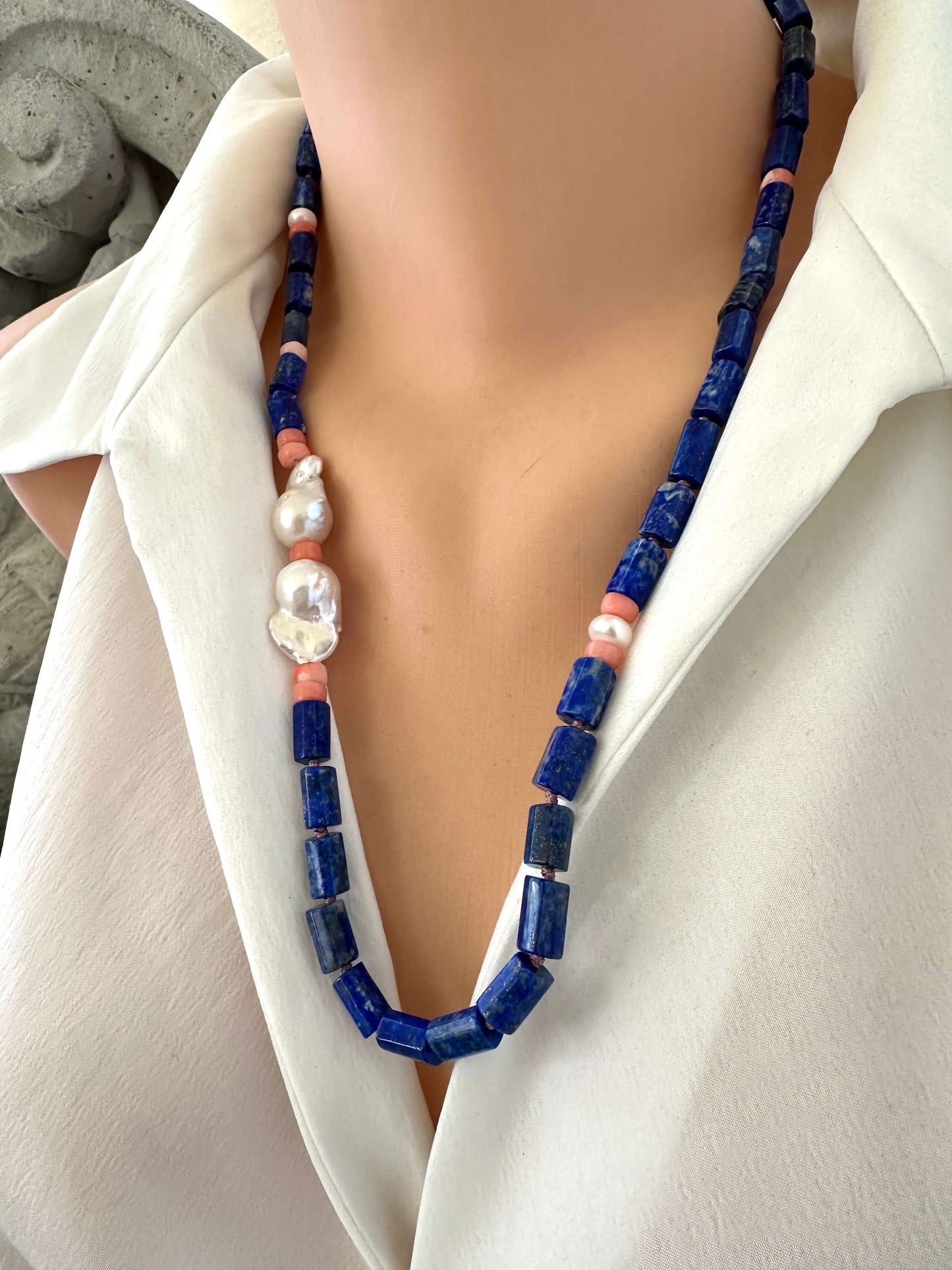 Lapis lazuli necklace with pink coral and baroque pearls, showcasing deep blue beads and elegant accents on a mannequin.